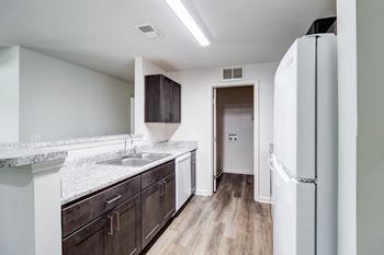 A kitchen with a white fridge and brown cabinets.